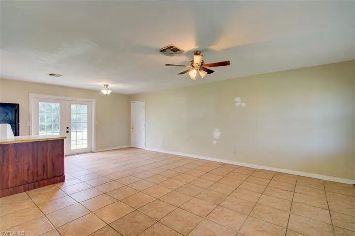 Unfurnished room featuring light tile patterned floors, ceiling fan, and french doors