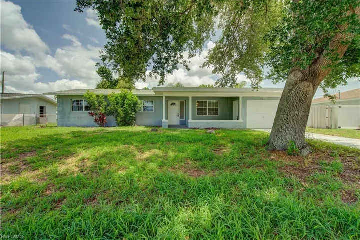 Ranch-style house with an attached garage, concrete block siding, covered porch, and concrete driveway