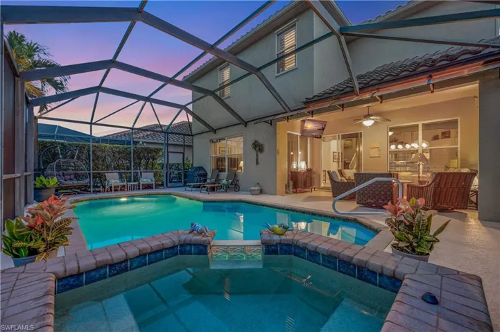 Pool at dusk with a patio, ceiling fan, and a lanai