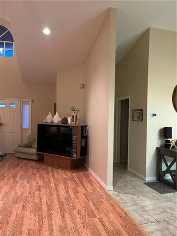 Vaulted ceiling with an arched window, featuring recessed lighting and wood-finish flooring