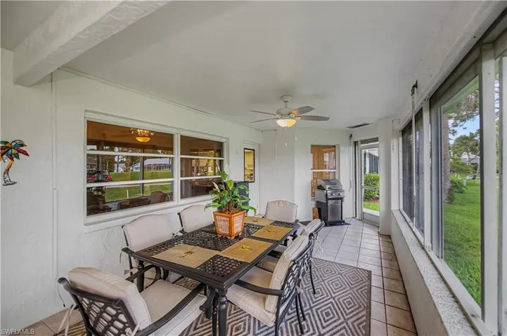 Screened lanai featuring white walls, a ceiling fan, and tile flooring