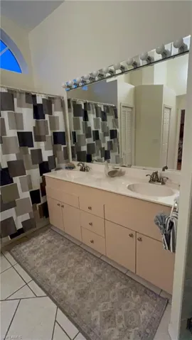 Dual vanity with integrated sinks, a large wall-mounted mirror, and overhead strip lighting