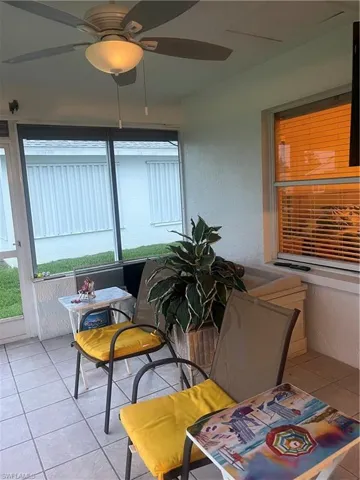 Screened patio featuring a ceiling fan with integrated lighting, tile flooring, and multiple windows with horizontal blinds