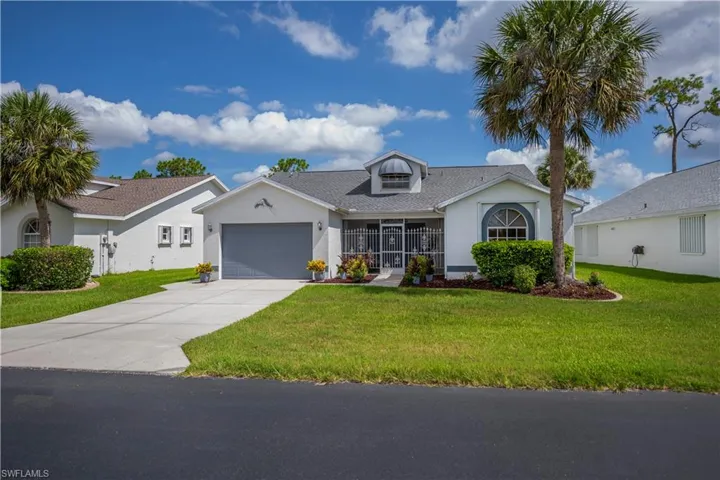 Single-story residence featuring a gray garage door, screened front entry, and arched window with decorative trim