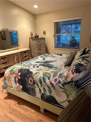 Spacious room featuring wood-finish flooring and a window with horizontal blinds