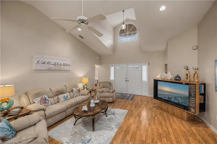 Spacious living area featuring vaulted ceilings, wood-finish flooring, and a ceiling fan