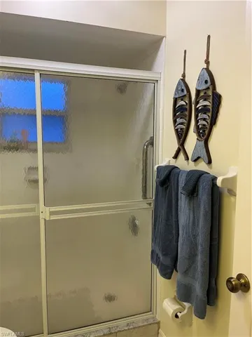 Frosted glass shower enclosure with white framing, featuring a sliding door and a polished metal handle