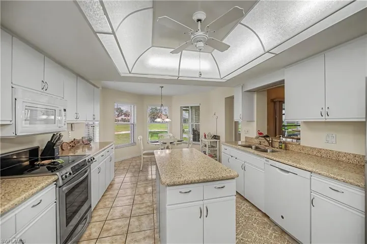Bright kitchen featuring white cabinetry, light-toned countertops, tile flooring, and a central island