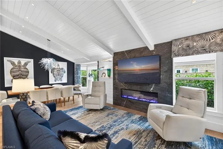 Living area with wood finished floors, a fireplace, and vaulted ceiling with beams