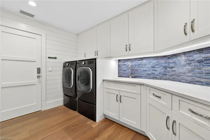 Laundry room with light wood-style flooring, washing machine and dryer, and cabinet space