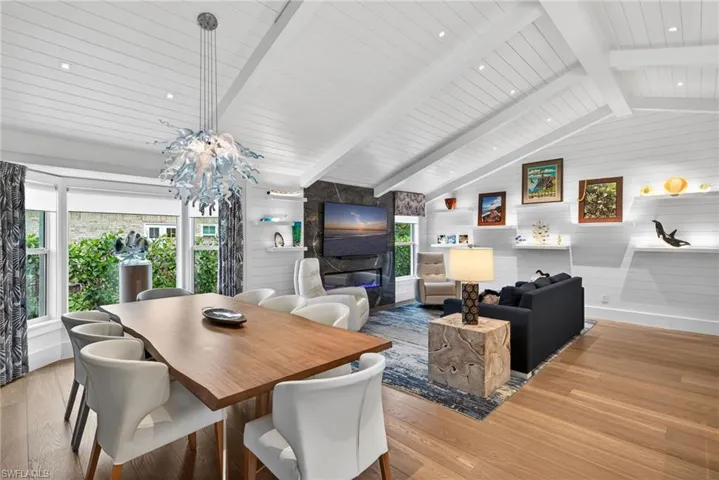 Dining area featuring wood walls, wood finished floors, and vaulted ceiling with beams