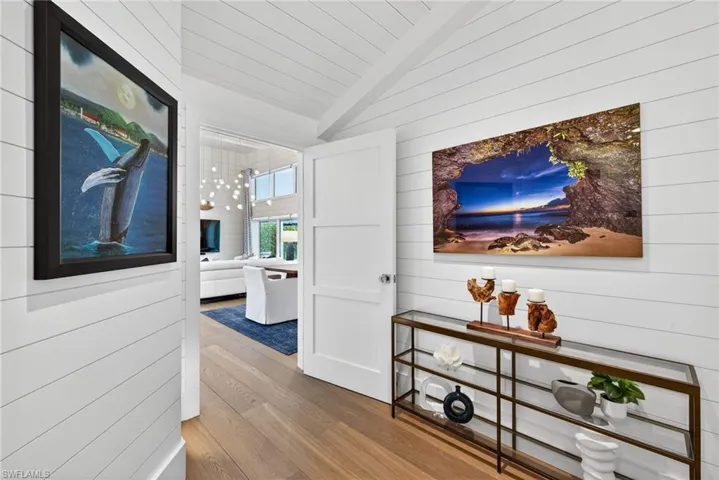 Hallway with light wood-style flooring, wooden walls, wood ceiling, and lofted ceiling with beams