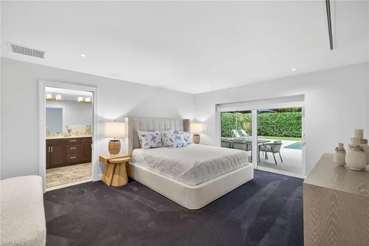 Bedroom with dark carpet, access to outside, ensuite bathroom, and recessed lighting