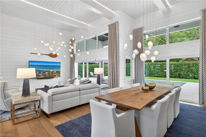 Dining area featuring wood finished floors, wood walls, suspended lighting, and a high wood beamed ceiling