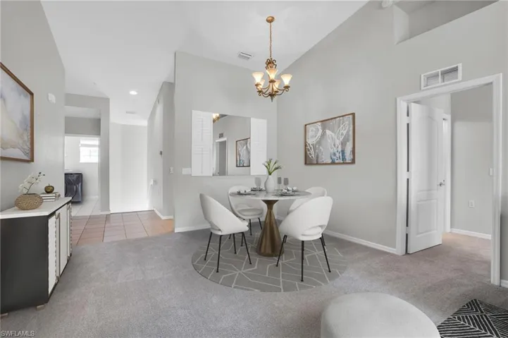 Carpeted dining area with an inviting chandelier and lofted ceiling
