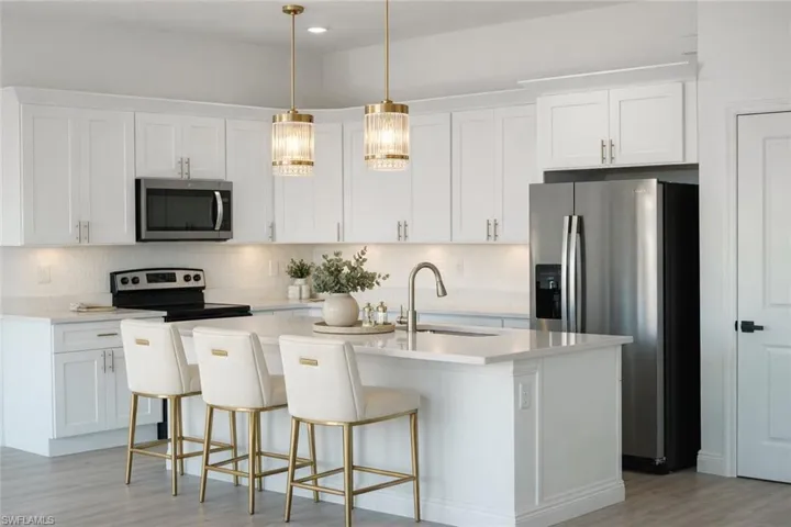 The kitchen features white cabinetry, stainless steel appliances, and a central island with counter seating