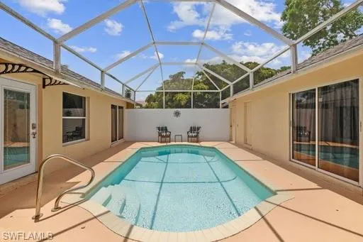 View of pool with a patio and glass enclosure