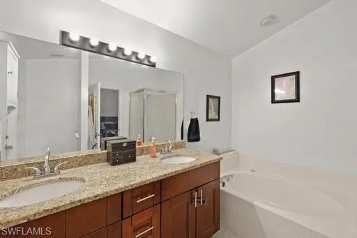 Bathroom with a relaxing tiled bath, lofted ceiling, and double sink vanity