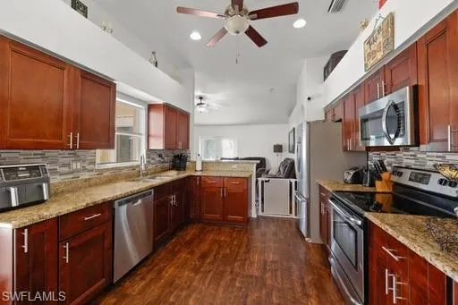 Kitchen with stainless steel appliances, dark hardwood / wood-style floors, backsplash, sink, and ceiling fan