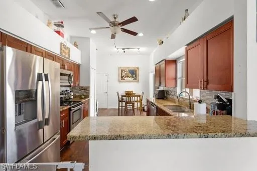 Kitchen with appliances with stainless steel finishes, sink, and light stone countertops