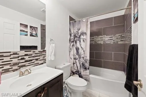 Full bathroom with tile floors, toilet, tasteful backsplash, shower / bath combination with curtain, and oversized vanity