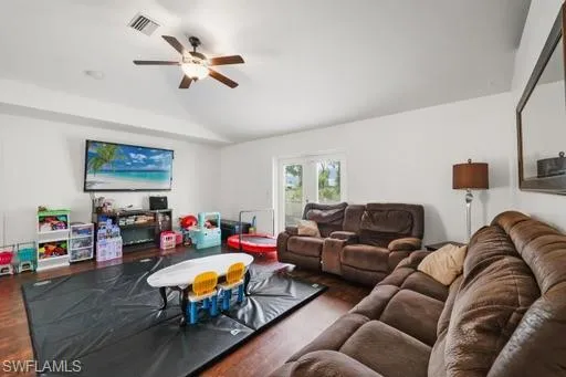Living room featuring lofted ceiling, ceiling fan, and dark hardwood / wood-style flooring