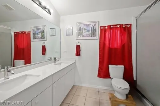 Bathroom with tile flooring, oversized vanity, toilet, and double sink