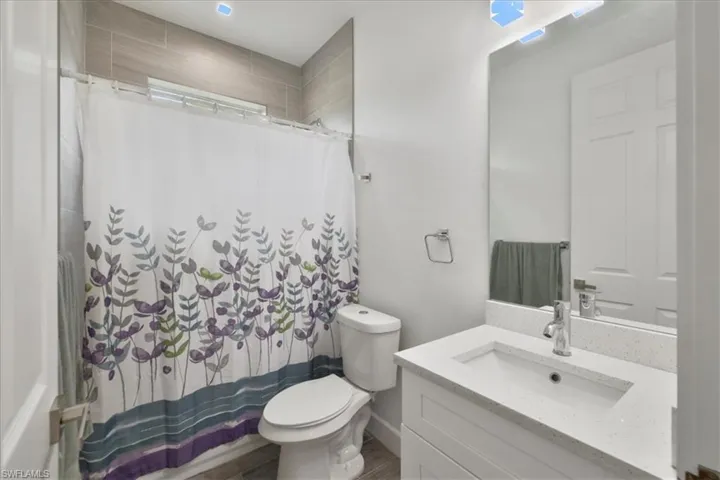 Bathroom featuring toilet, vanity, a shower with curtain, and wood finished floors