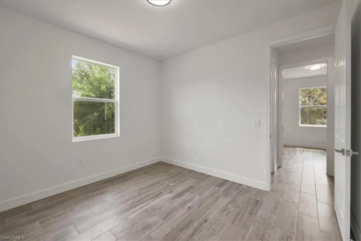 Empty room featuring plenty of natural light, light wood-style floors, and baseboards