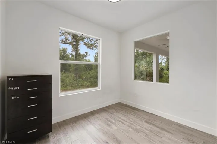 Empty room with healthy amount of natural light, light wood-style floors, and baseboards
