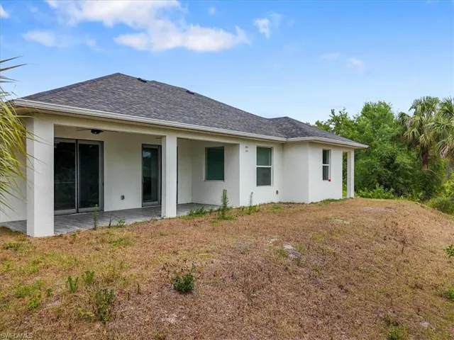 Rear view of house with a patio, stucco siding, and a shingled roof