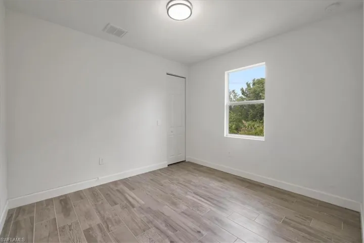Empty room featuring wood finished floors, baseboards, and a smoke detector