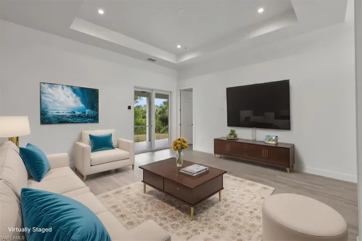 Living room featuring wood finished floors, a raised ceiling, recessed lighting, and baseboards