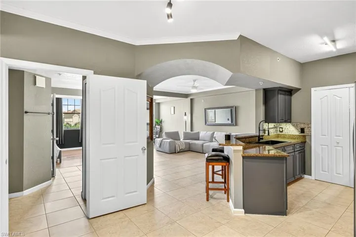 Kitchen with a peninsula, dark stone countertops, a kitchen breakfast bar, a ceiling fan, and arched walkways