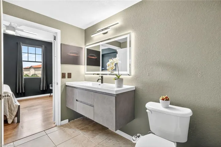 Half bathroom featuring a textured wall, vanity, and light tile patterned flooring