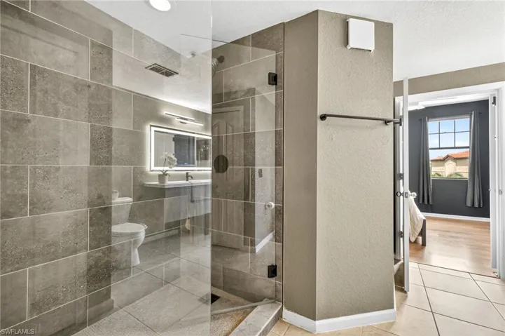 Full bath featuring a textured wall, a shower stall, and light tile patterned floors