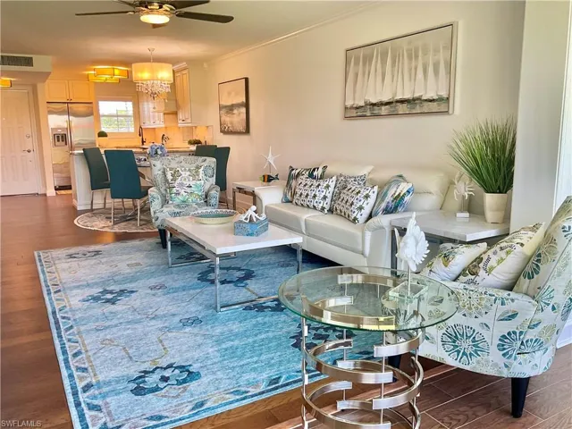 Living room featuring ceiling fan with notable chandelier, crown molding, and dark hardwood / wood-style floors