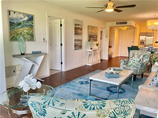 Living room with hardwood / wood-style flooring and ceiling fan with notable chandelier