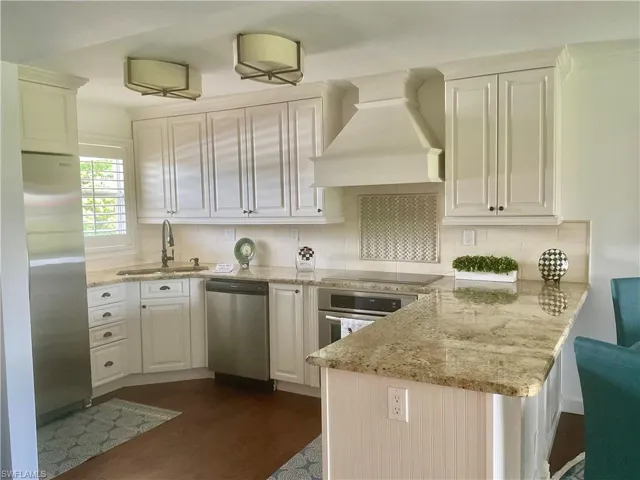 Kitchen featuring appliances with stainless steel finishes, tasteful backsplash, sink, dark wood-type flooring, and custom range hood