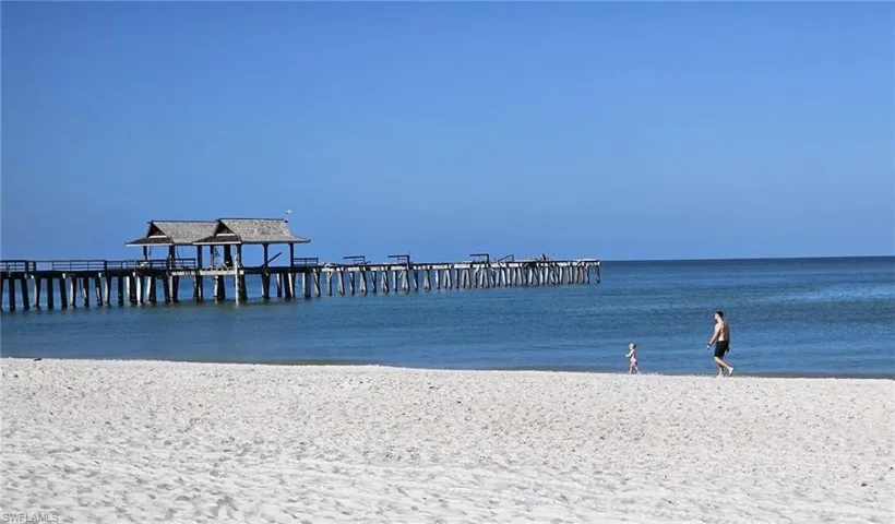 Dock area featuring a pier and view of water and beach