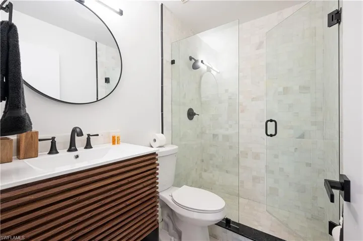 Bathroom with toilet, a shower with door, and vanity