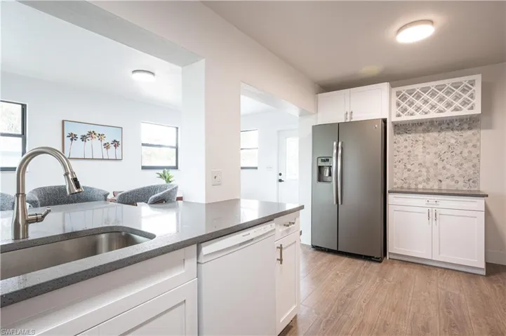 Kitchen with dishwasher, stainless steel fridge with ice dispenser, light hardwood / wood-style floors, sink, and white cabinets