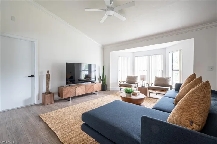 Living room featuring ornamental molding, lofted ceiling, hardwood / wood-style floors, and ceiling fan