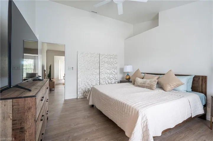 Bedroom with ceiling fan, a towering ceiling, and hardwood / wood-style flooring