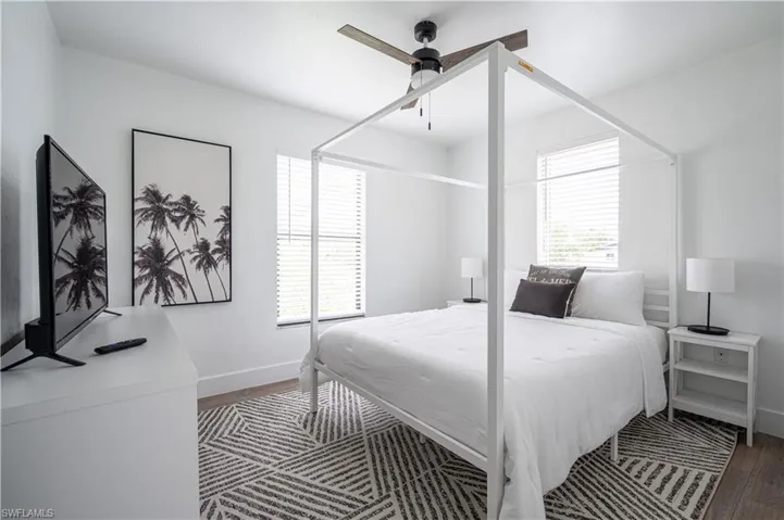 Bedroom with dark wood-type flooring, multiple windows, and ceiling fan