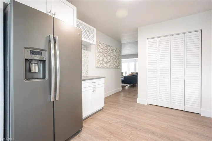 Kitchen with stainless steel refrigerator with ice dispenser, white cabinetry, and light hardwood / wood-style floors