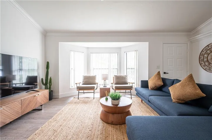 Living room featuring wood-type flooring, a wealth of natural light, and crown molding