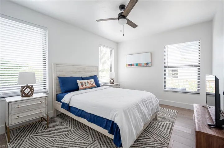Bedroom with dark wood-type flooring, ceiling fan, and multiple windows