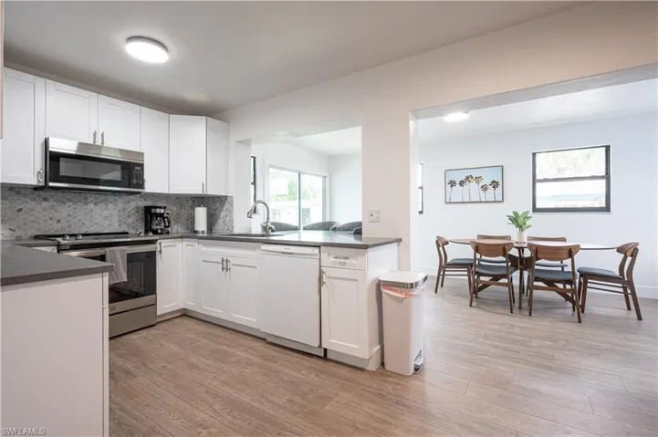 Kitchen with light hardwood / wood-style flooring, white cabinets, stainless steel appliances, and sink
