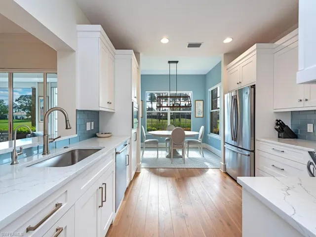 Kitchen with pendant lighting, backsplash, white cabinets, sink, and stainless steel appliances